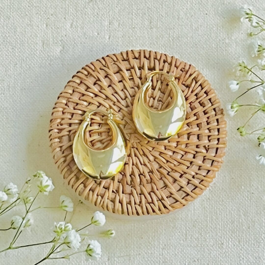 Gold earrings on woven coaster