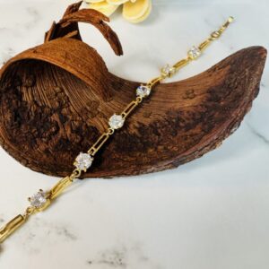 Gold bracelet with clear gemstones on wood