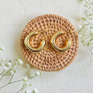 Chunky gold hoop earrings on woven coaster