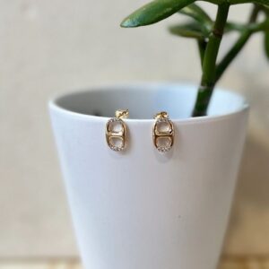 Gold oval stud earrings on white cup