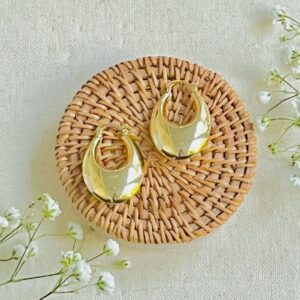Gold crescent hoop earrings on rattan coaster